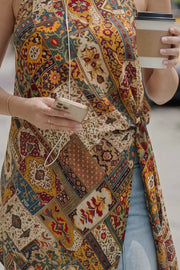 Blusa larga estampada de fit fluido, cuello halter, sin mangas, bajo asimétrico, plisados en costado con abertura y nudo decorativo , cierre posterior con botón y ojal.