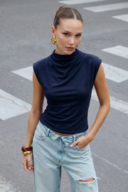 Top corto de fit ajustado, manga corta seguida, cuello mock seguido y plisados decorativos en hombros.