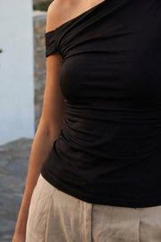 Top ajustado sin mangas, de cuello diagonal con hombro descubierto, plisados en hombros y costados.