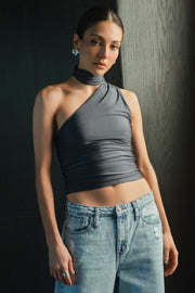 Top satinado asimétrico, de fit ajustado, detalles plisados laterales y en hombro, sin mangas, un hombro, escote diagonal y choker con plisados. Cierre posterior con botón y ojal.