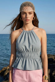 Top corto de cuello halter con plisados, tirantes delgados, detalle de rib con plisados y lazos laterales en costados, peplum con olanes en bajo y cierre posterior con botón y ojal.