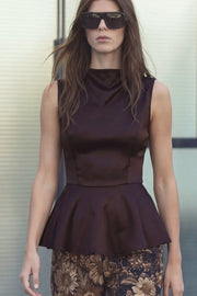 Blusa de fit ajustado, cuello alto fluido, sin mangas, peplum con olanes en bajo, cierre posterior con botón y ojal.