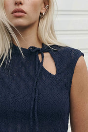 Top corto ajustado, sin mangas, cuello mao con cut out lateral y lazo amarrable. Detalle de textura en tejido.