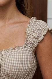 Top corto de estampado cuadros, escote v redondeado y manga corta con rib elástico y olanes en borde, elástico en cintura y peplum con olanes en bajo.
