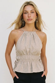 Top corto de cuello halter con plisados, tirantes delgados, detalle de rib con plisados y lazos laterales en costados, peplum con olanes en bajo y cierre posterior con botón y ojal.