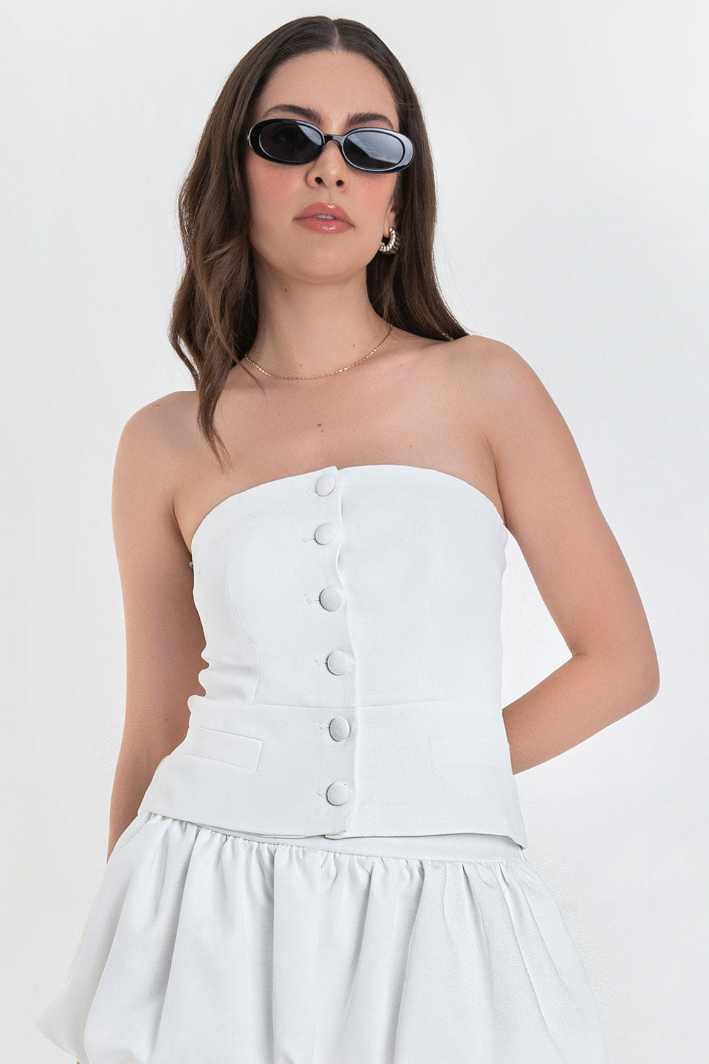 Top tubo de fit ajustado, strapless, escote recto, corte en cintura, vivos decorativos y cierre frontal con hilera de botones forrados.
