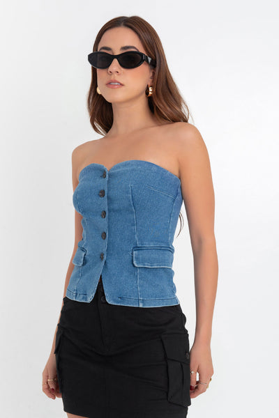 Top strapless de denim, fit ajustado, escote corazón, bolsillos frontales decorativos con cartera, pinzas frontales, detalle de bajo curveado y cierre con hilera de botones en contraste.