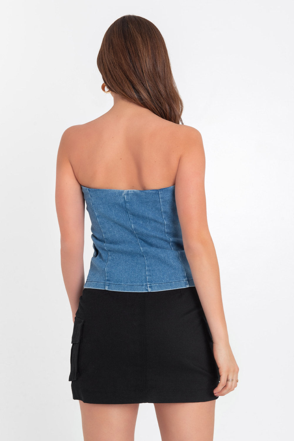 Top strapless de denim, fit ajustado, escote corazón, bolsillos frontales decorativos con cartera, pinzas frontales, detalle de bajo curveado y cierre con hilera de botones en contraste.