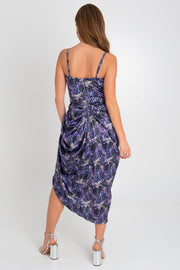 Vestido midi estampado, de tirantes delgados ajustables, escote corazón con cortes y costuras de corset en talle. Bajo asimétrico, cruce frontal con plisados y abertura. Detalle de plisados posteriores decorativos y cierre posterior con cremallera visible en contraste.