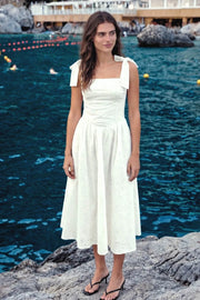 Vestido midi de bordado floral con perforado, tirantes con nudo amarrable, escote recto con cortes y plisados decorativos, corte en a, plisados en cintura con corte frontal en v y fruncido en espalda.