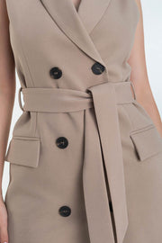 Vestido chaleco corto de fit recto, con solapa, bolsillos frontales con cartera, trabillas y cinturón amarrable del mismo tejido. Cierre frontal con doble cruce de botones.