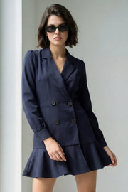 Vestido corto cruzado tipo blazer, fit ajustado, de manga larga abullonada con puño abotonado, solapa, doble cruce de botones y bajo con olanes en borde.