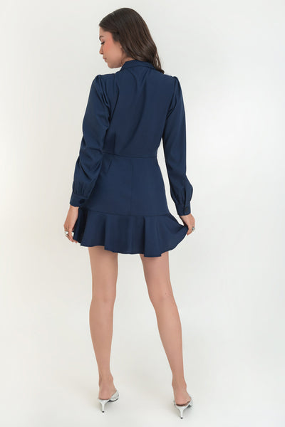 Vestido corto cruzado tipo blazer, fit ajustado, de manga larga abullonada con puño abotonado, solapa, doble cruce de botones y bajo con olanes en borde.