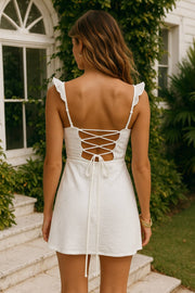 Vestido corto de escote v con plisados frontales, corte en a, tirantes ajustables con olanes en hombros, lazado ajustable en espalda y cierre posterior con cremallera oculta.
