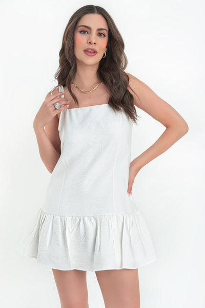 Vestido corto de fit fluido, tirantes delgados con nudo amarrable, escote recto, costuras frontales, corte en cadera y bajo con olanes. Cierre posterior con cremallera oculta.