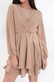 Vestido corto de manga larga abullonada con rib elástico en puños, escote v cruzado, trabillas y cinturón amarrable del mismo tejido. Detalle de bajo con capas de olanes y cierre posterior con cremallera oculta.
