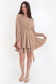 Vestido corto de manga larga abullonada con rib elástico en puños, escote v cruzado, trabillas y cinturón amarrable del mismo tejido. Detalle de bajo con capas de olanes y cierre posterior con cremallera oculta.