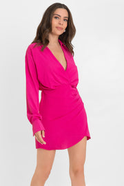 Vestido corto de manga larga con puño abotonado, escote v cruzado con detalles plisados, cuello camisero, fit ajustado y plisado lateral con bajo curveado frontal. Cierre lateral con cremallera oculta.