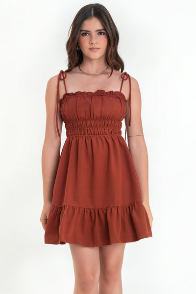 Vestido corto de escote recto con plisados, rib y olanes en borde, tirantes delgados con nudo amarrable, fruncido con rib elástico y plisados en cintura, corte en a y bajo con olanes en borde.