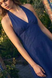 Vestido corto de cuello halter con lazo amarravle posterior, sin mangas, escote v con cortes y plisados frontales, corte en a, cortes frontales y escote en espalda. Cierre posterior con cremallera oculta.