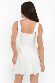 Vestido corto de fit recto, escote v con cortes y plisados decorativos, tirantes con nudo amarrable y cierre posterior con cremallera oculta.