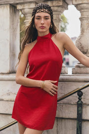 Vestido corto de fit ajustado, cuello halter alto, sin mangas, escote en espalda, cierre posterior con botón en contraste, ojal y cremallera oculta.