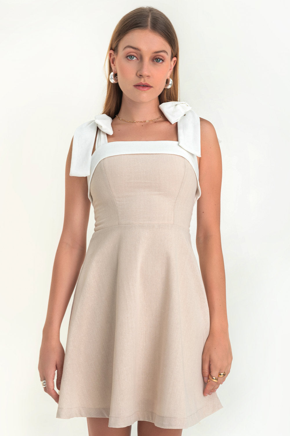 Vestido corto de lino, tirantes con nudo amarrable, escote recto con doblez en borde, corte en a y cierre posterior con cremallera oculta.