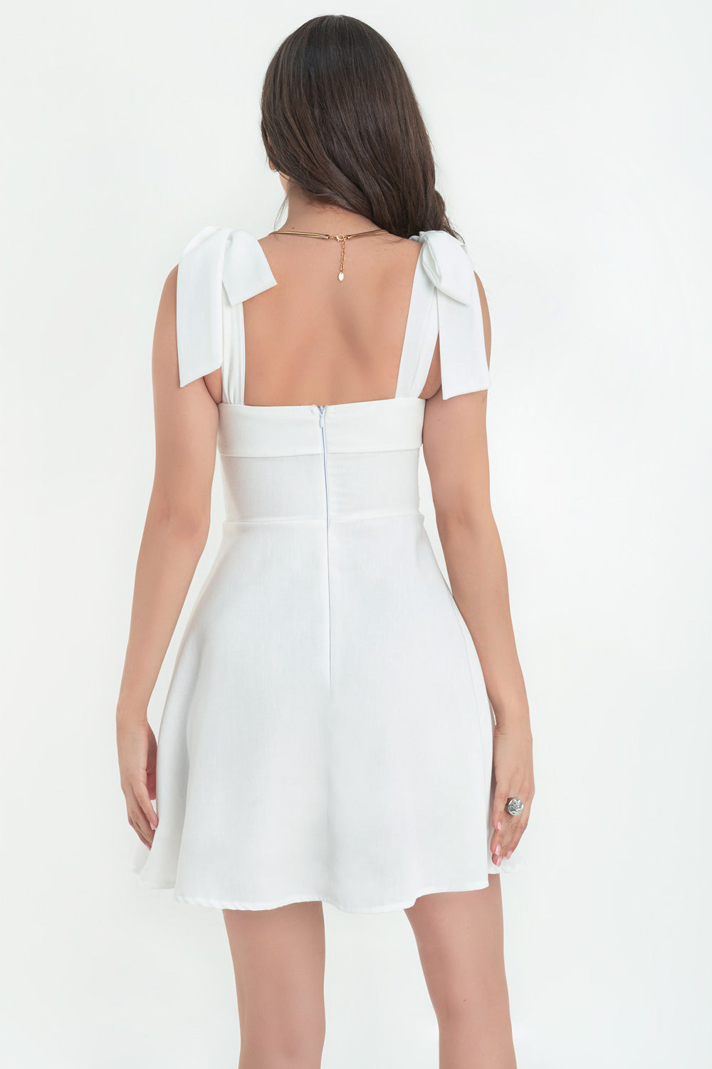 Vestido corto de lino, tirantes con nudo amarrable, escote recto con doblez en borde, corte en a y cierre posterior con cremallera oculta.