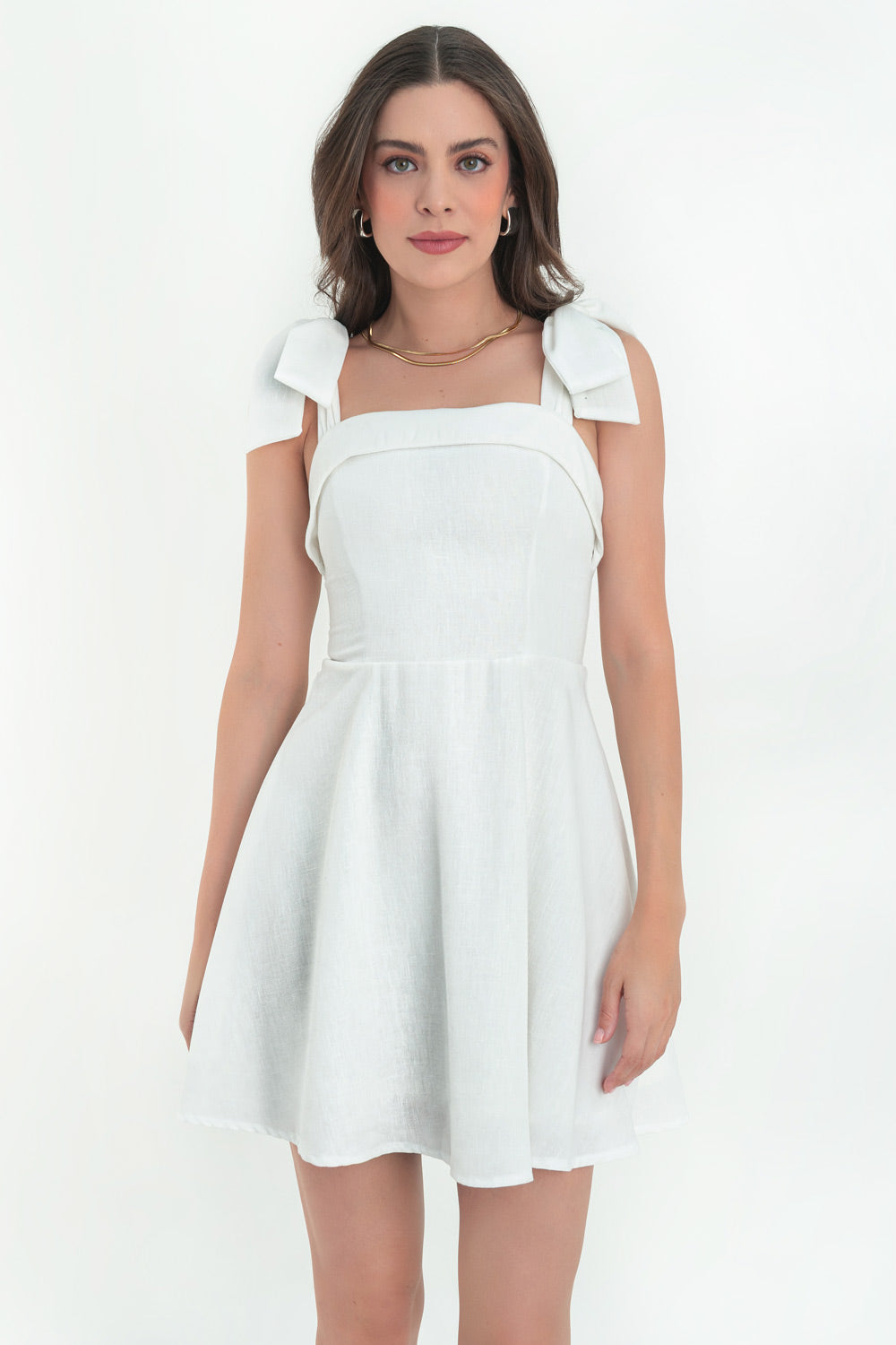 Vestido corto de lino, tirantes con nudo amarrable, escote recto con doblez en borde, corte en a y cierre posterior con cremallera oculta.