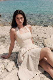 Vestido midi de lino, cuello halter, sin mangas, escote recto, corte en a, corte v en cintura con plisados y fruncido en espalda.