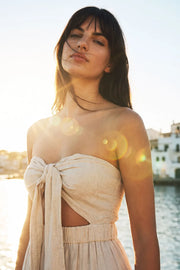 Vestido midi strapless de lino, escote corazón con nudo amarrable, cut out frontal, cintura elástica, detalle de capas de olanes en bajo y fruncido en espalda.