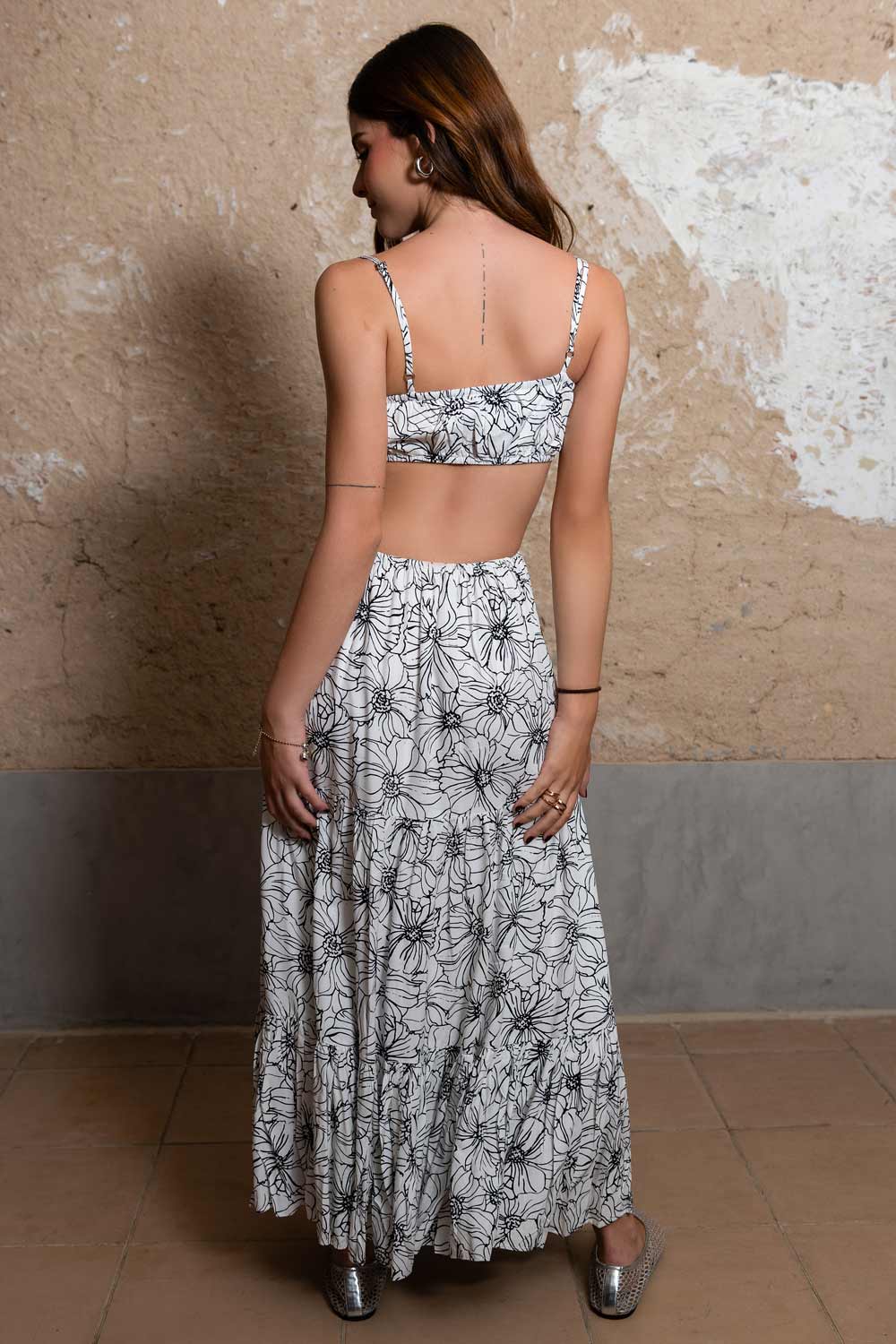 Maxi vestido de estampado floral, escote recto con plisados frontales, tirantes delgados ajustables, cut out en costados y espalda, rib elástico en cintura y detalle de capas de olanes en bajo.