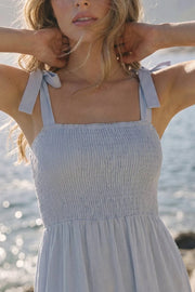 Vestido maxi de tirantes con nudo amarrable, talle fruncido, escote recto y corte en a con capas de olanes en bajo.