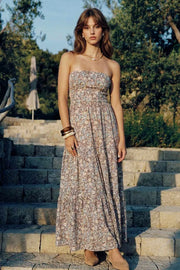Vestido midi strapless de estampado floral, escote recto, cut out en espalda con nudo amarrable, cintura elástica, detalle de capas de olanes en bajo y fruncido en espalda.