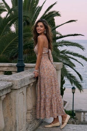 Vestido midi strapless de estampado floral, escote recto, cut out en espalda con nudo amarrable, cintura elástica, detalle de capas de olanes en bajo y fruncido en espalda.