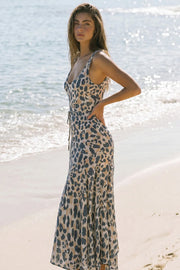 Vestido midi de corte en a, estampado animal, sin mangas, escote v con cortes frontales decorativos, bajo asimétrico con olanes, escote fluido en espalda y lazo amarrable en cintura.