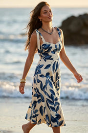 Vestido midi estampado de tirantes con nudo amarrable, escote corazón con plisados y cortes decorativos frontales, corte en a y cierre posterior con cremallera oculta.