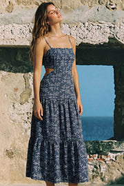 Vestido midi de estampado floral, corte en a, tirantes delgados con nudo amarrable, bajo con capas de olanes, cut out en costados y espalda. Detalle de rib elástico en cintura y fruncido en espalda.