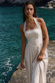 Vestido midi de lino, cuello halter con rib elástico, sin mangas, escote recto, cortes frontales, detalle frontal v en cintura con plisados y fruncido en espalda.
