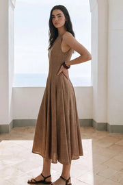Vestido midi de lino, sin mangas, corte en a, cuello barco, escote en espalda y cortes frontales decorativos. Cierre lateral con cremallera oculta.