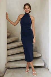 Vestido midi de fit ajustado, cuello alto halter, sin mangas, plisados en costados y abertura lateral en bajo. Cierre posterior con botones y ojales.