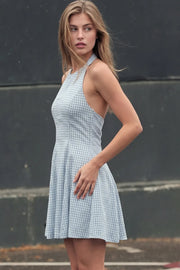 Vestido corto de estampado cuadros, cuello halter, sin mangas, escote en espalda, corte en a con pinzas y cierre posterior con cremallera oculta y botón.
