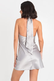 Vestido corto satinado de fit ajustado, cuello halter con nudo frontal y lazo amarrable posterior. Cierre con cremallera oculta posterior.