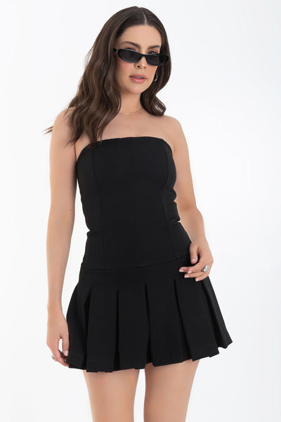 Vestido corto de fit ajustado, strapless, escote recto, cortes frontales decorativos y bajo con tableado. Cierre posterior con cremallera visible en contraste.