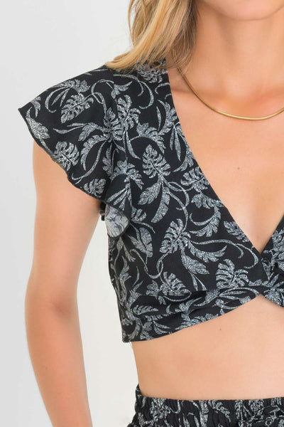 Crop top de estampado floral, fit ajustado, manga corta con olanes y escote v con nudo frontal. Cierre lateral con cremallera oculta.