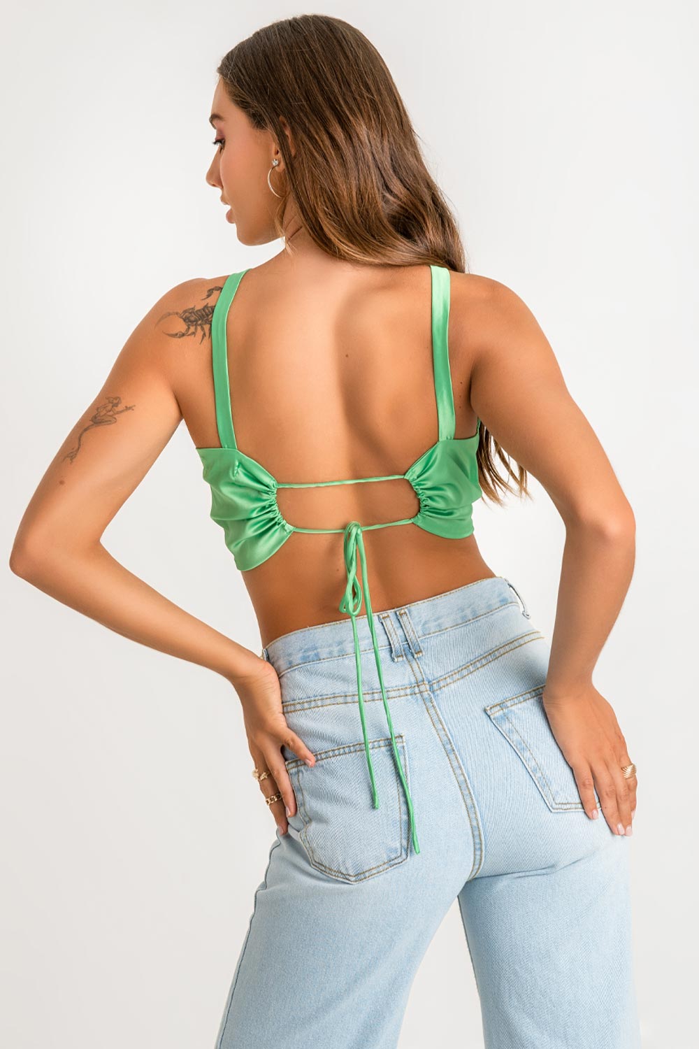 Crop top satinado de fit ajustado, tirantes, cuello halter con nudo frontal y cut out en escote. Escote en espalda y cierre posterior con jareta ajustable.