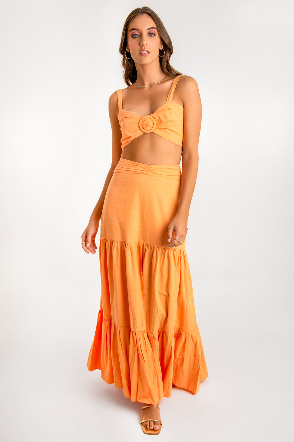 Crop top de lino, fit ajustado, tirantes, escote corazón con detalles plisados y argolla decorativa frontal. Cierre posterior con lazo amarrable.